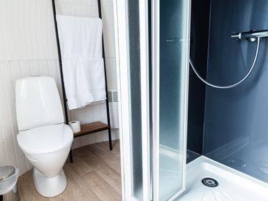 A bathroom with a toilet a towel rack with white towels and a shower at Andrus - Mayflower Meadow in Brandesburton