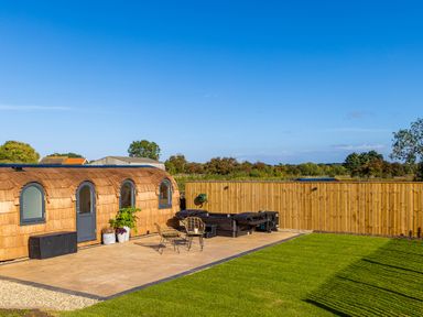 An outdoor area with a small wooden pod structure patio furniture hot tub and a wooden fence at Andrus - Mayflower Meadow in Brandesburton