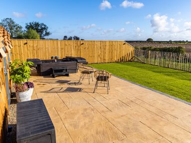 A patio with two chairs and a hot tub next to a grassy area with wooden fencing at Andrus - Mayflower Meadow in Brandesburton
