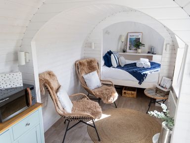 A small room with two wicker chairs with cushions a bed with blue and white bedding a round woven rug and a microwave on a cabinet at Andrus - Mayflower Meadow in Brandesburton