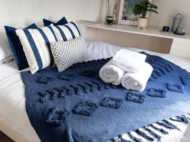 A bed with blue and white pillows folded towels and a blue textured blanket at Andrus - Mayflower Meadow in Brandesburton