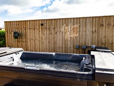 An outdoor hot tub with water and a wooden fence with a sign saying Mayflower Meadow in Brandesburton