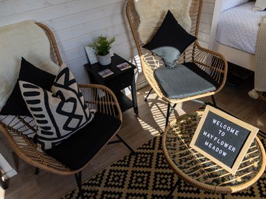 Two rattan chairs with cushions around a small glass table with welcome sign and black side table with plant in a room at Indrek - Mayflower Meadow in Brandesburton