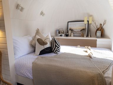 A bedroom with a bed and pillows next to a shelf with decor and a framed picture at Indrek - Mayflower Meadow in Brandesburton