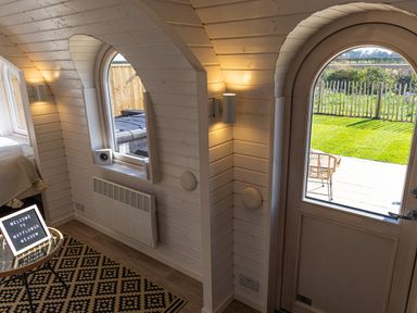 An interior room with a wooden arched door and window showing a garden outside at Indrek - Mayflower Meadow in Brandesburton