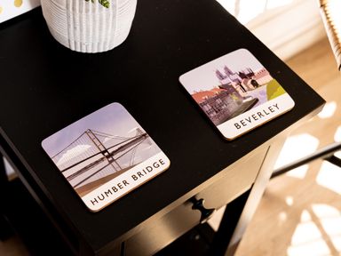 A black side table with two coasters labeled Humber Bridge and Beverley and a white pot with a plant at Indrek - Mayflower Meadow in Brandesburton