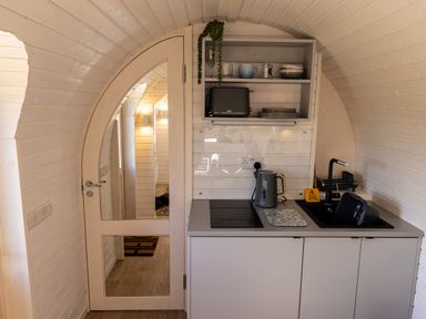 A small kitchen area with a sink toaster kettle and dishes next to a wooden door with glass at Indrek - Mayflower Meadow in Brandesburton