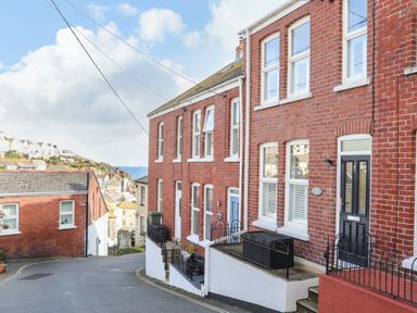 A street view of brick houses with windows and doors near a coastal area at Chy An Mor in Mevagissey