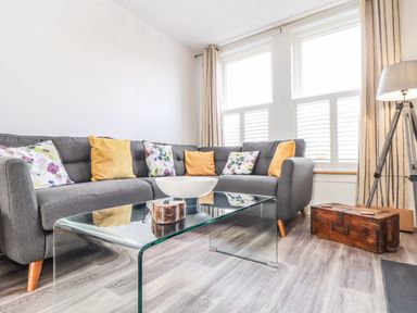 A living room with a gray sofa and glass coffee table near windows at Chy An Mor in Mevagissey