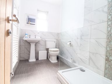 A bathroom with a pedestal sink toilet shower and tiled walls at Chy An Mor in Mevagissey