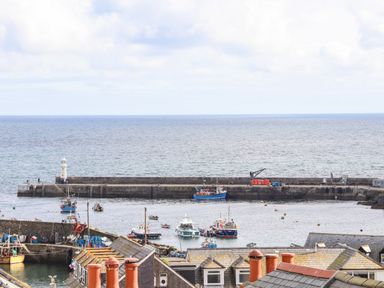 A harbor with boats and a lighthouse by the sea at Chy An Mor in Mevagissey