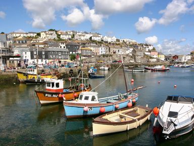 A harbor with boats moored in the water and houses on a hillside at Chy An Mor in Mevagissey