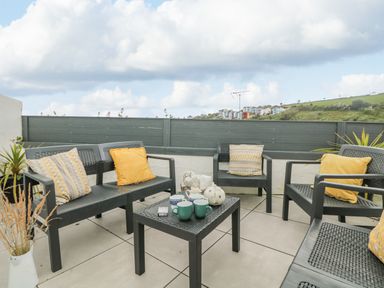 An outdoor patio with chairs and a table with mugs and a teapot at Chy An Mor in Mevagissey