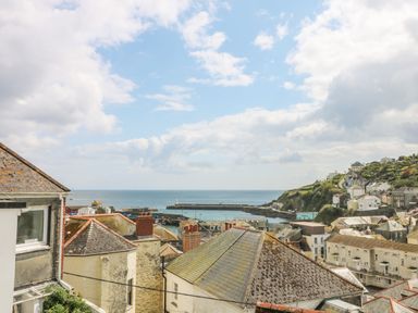 A view of rooftops with a harbor and ocean in the background at Chy An Mor in Mevagissey