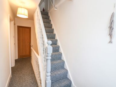 A hallway with carpeted stairs and a wooden door at Chy An Mor in Mevagissey