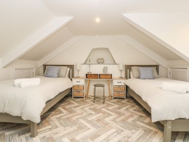 A bedroom with two single beds a desk and a stool at Chy An Mor in Mevagissey