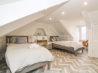 A bedroom with two beds and a desk under a sloped ceiling at Chy An Mor in Mevagissey