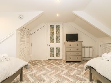 A bedroom with two beds a dresser and a television at Chy An Mor in Mevagissey