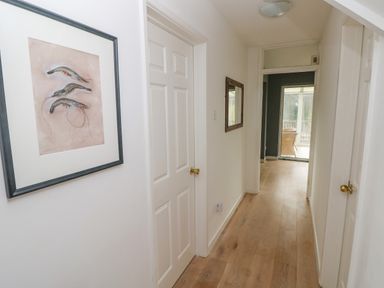 A hallway with wooden flooring white doors a framed picture on the left wall and a mirror on the right wall at Old Orchard in Saundersfoot