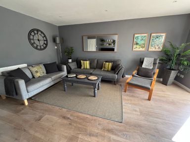 A living room with two sofas a single armchair a coffee table and wall decorations at Old Orchard in Saundersfoot