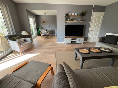 A living room with chairs a coffee table a television on a stand shelves with plants and pictures at Old Orchard in Saundersfoot