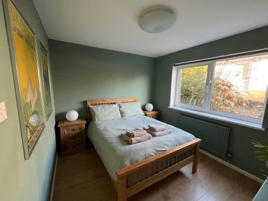 A bedroom with a wooden bed and two bedside tables with lamps near a window at Old Orchard in Saundersfoot