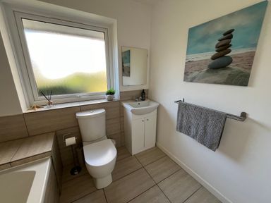 A bathroom with a toilet sink bathtub window and towel hanging on a rack at Old Orchard in Saundersfoot