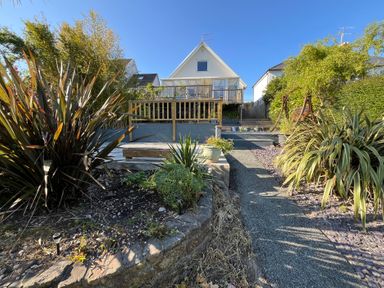 A garden with plants a pathway and a house with a balcony at Old Orchard in Saundersfoot