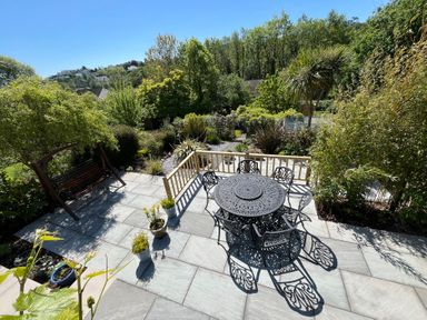 A garden patio with metal table and chairs swing seat and various plants at Old Orchard in Saundersfoot