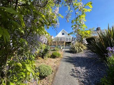 A garden path leading to a house with plants and flowers on both sides at Old Orchard in Saundersfoot