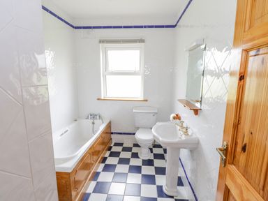 A bathroom with a bathtub wooden cabinet toilet sink and mirror at 13 Trawmore Cottages in Keel County Mayo