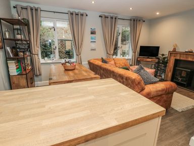 A living room with a brown sofa a wooden coffee table a shelving unit and a television at Dodds Nook in Alnwick