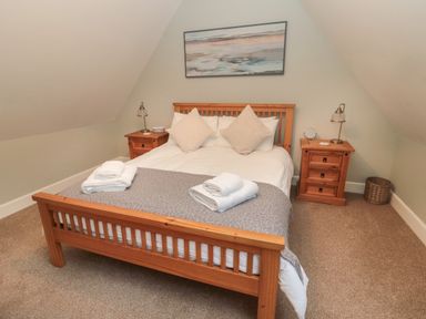A bedroom with a wooden bed frame bedside tables lamps and towels at Dodds Nook in Alnwick