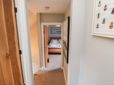 A hallway leading to a bedroom with a wooden bed frame and white bedding at Dodds Nook in Alnwick