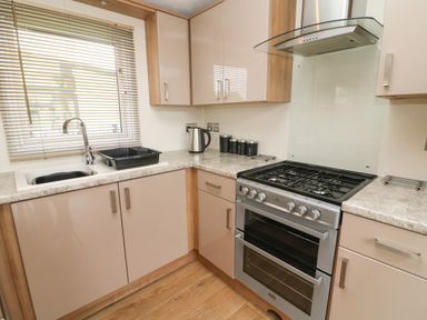 A kitchen with a gas stove oven sink kettle and cabinets at Waterside Lodge South Lakeland Leisure Village near Carnforth