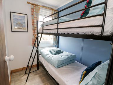 A bedroom with black metal bunk beds and a framed picture on the wall at Porthwen Lodge in Bull Bay near Cemaes Bay