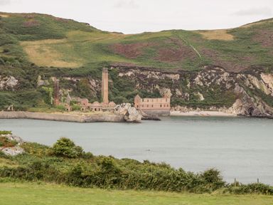 A coastal landscape with water green hills and old industrial buildings at Porthwen Lodge Bull Bay near Cemaes Bay