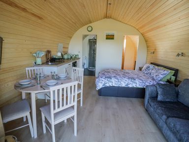 An open plan room with a dining table set for four a kitchenette a double bed and a sofa at Tamina in Hillhampton Great Witley