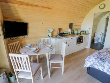 A small kitchen and dining area with a wall-mounted TV and a view into a bathroom at Tamina in Hillhampton Great Witley