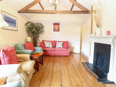 A living room with sofas wooden floor and a fireplace at Forge House in Cley Next The Sea