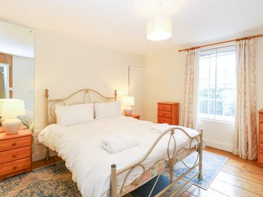 A bedroom with a metal bed frame two folded towels bedside tables lamps and a window at Forge House in Cley Next The Sea