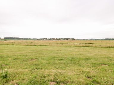 A large open grassy field with a village and hills in the background at Forge House in Cley Next The Sea