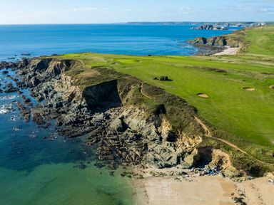 A coastal landscape with cliffs green fields and a sandy beach at Goody in Hope Cove