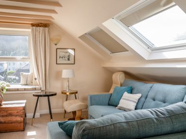 A living room with blue sofas a window seat with cushions two small tables a lamp and skylights at Goody in Hope Cove