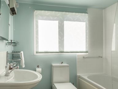 A bathroom with a sink a toilet a bathtub and a window with a blind at Goody in Hope Cove