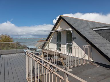 A rooftop terrace with picnic tables and a railing overlooking the sea at Goody in Hope Cove