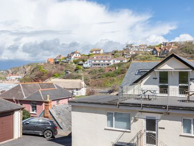Houses on a hillside with a car parked near a garage and a view of the beach at Goody in Hope Cove