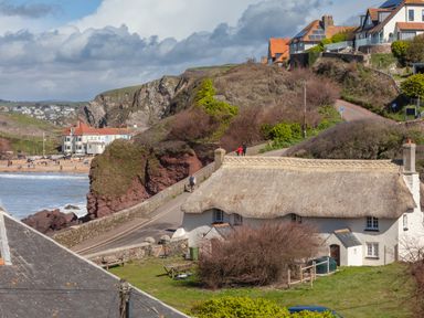 A coastal village with thatched cottages houses and cliffs near a beach at Goody in Hope Cove