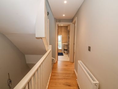 A hallway with wooden floor leading to a bathroom at Fishermans Cottage in Malltraeth