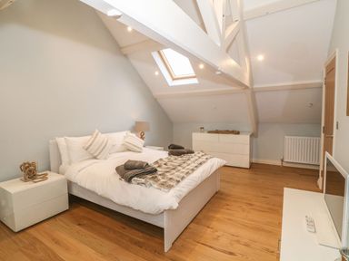 A bedroom with a double bed bedside tables dresser skylight and wooden floor at Fishermans Cottage Malltraeth